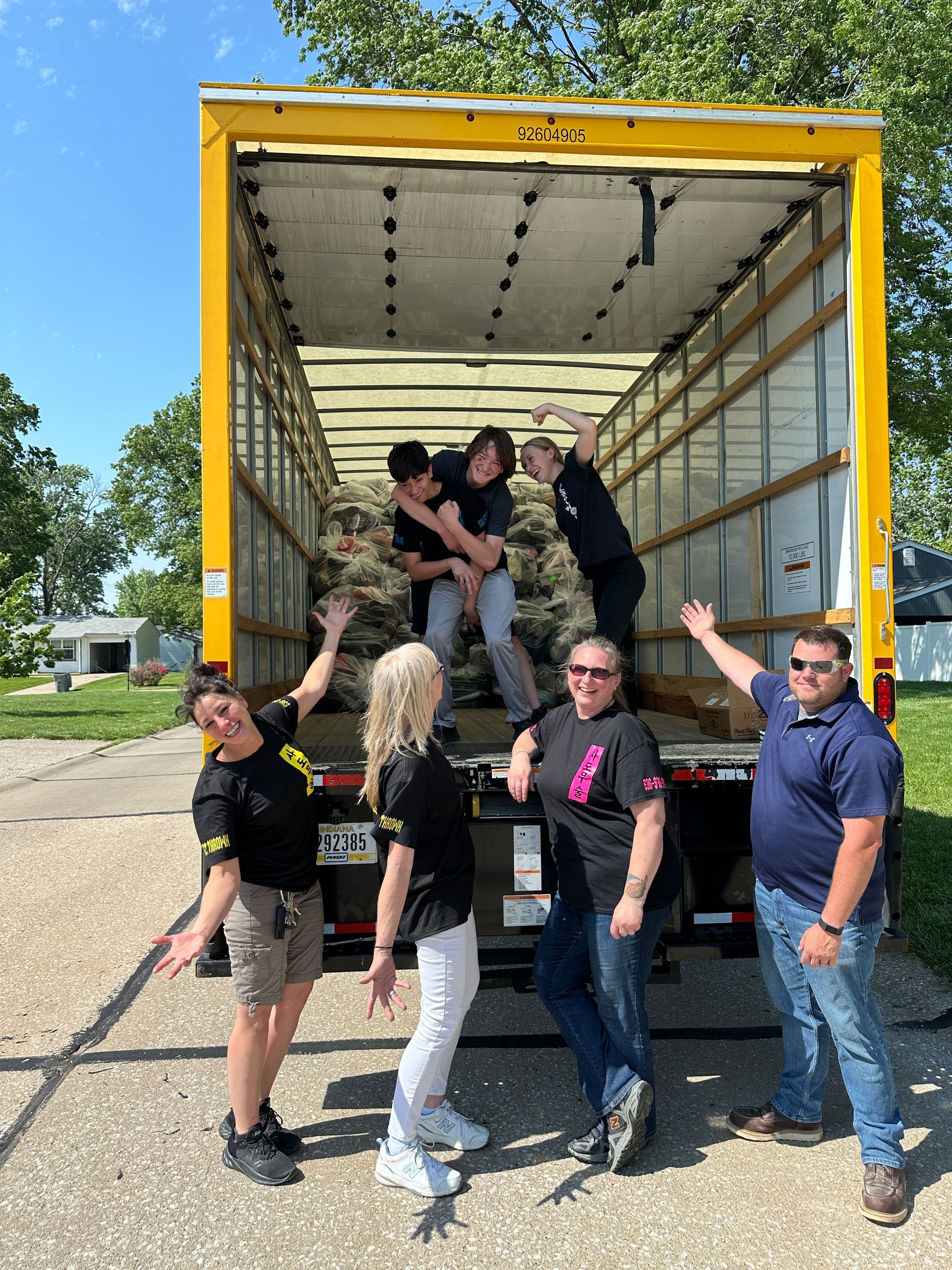 A group of people are standing in front of a moving truck.