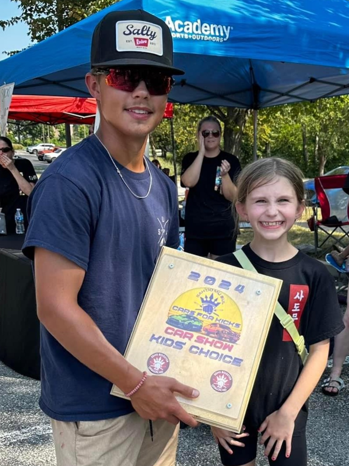 A man and a girl are standing next to each other holding a certificate.