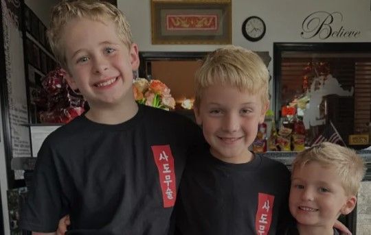 Three young boys wearing black shirts with the number 4 on them