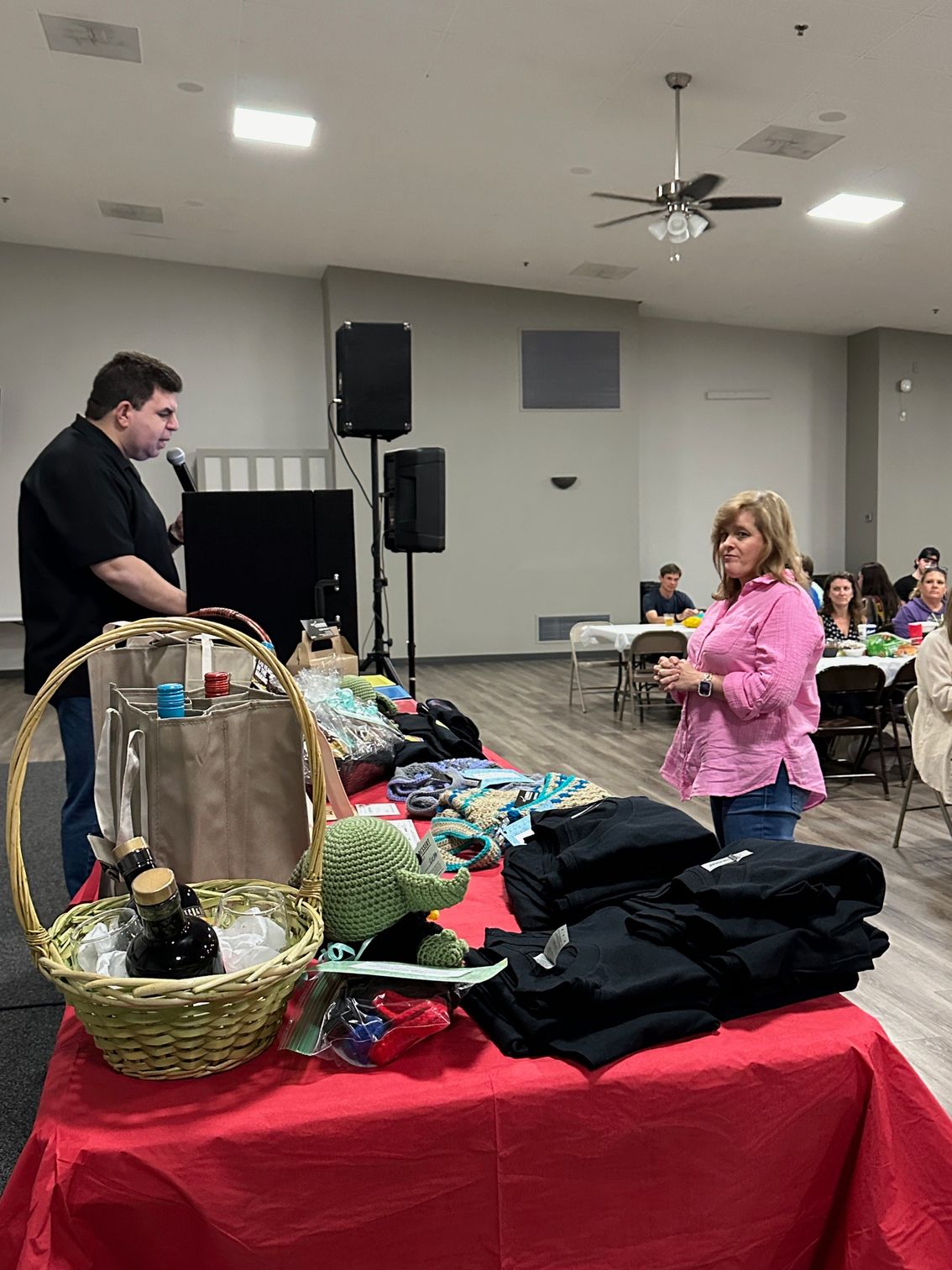 A man and a woman are standing in front of a table with a lot of items on it.