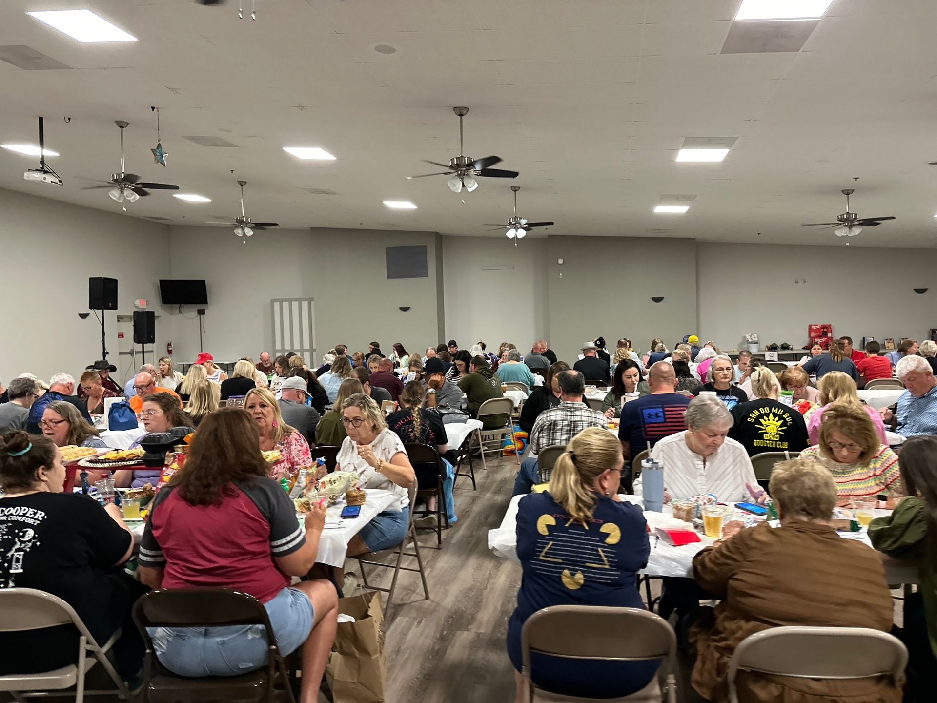 A large group of people are sitting at tables in a large room.