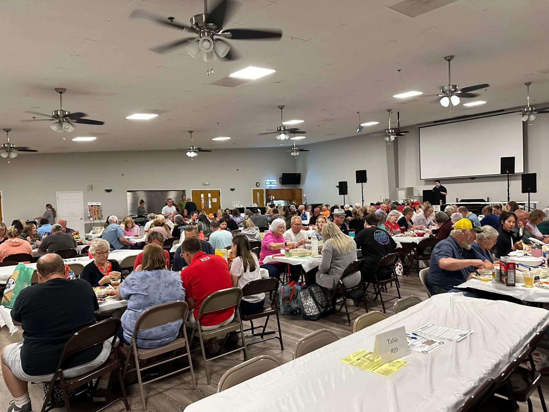 A large group of people are sitting at tables in a large room.