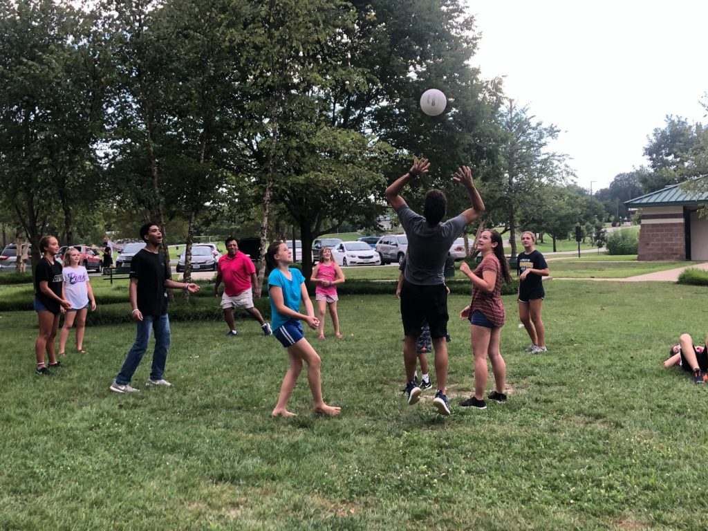 A group of people are playing volleyball in a park.