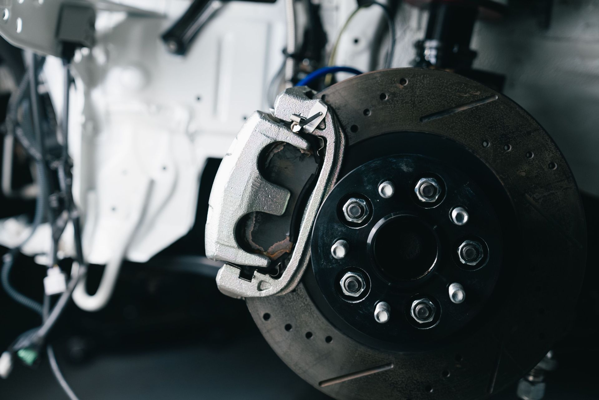 Close-up of a car brake disc and caliper with wheel removed in a garage.