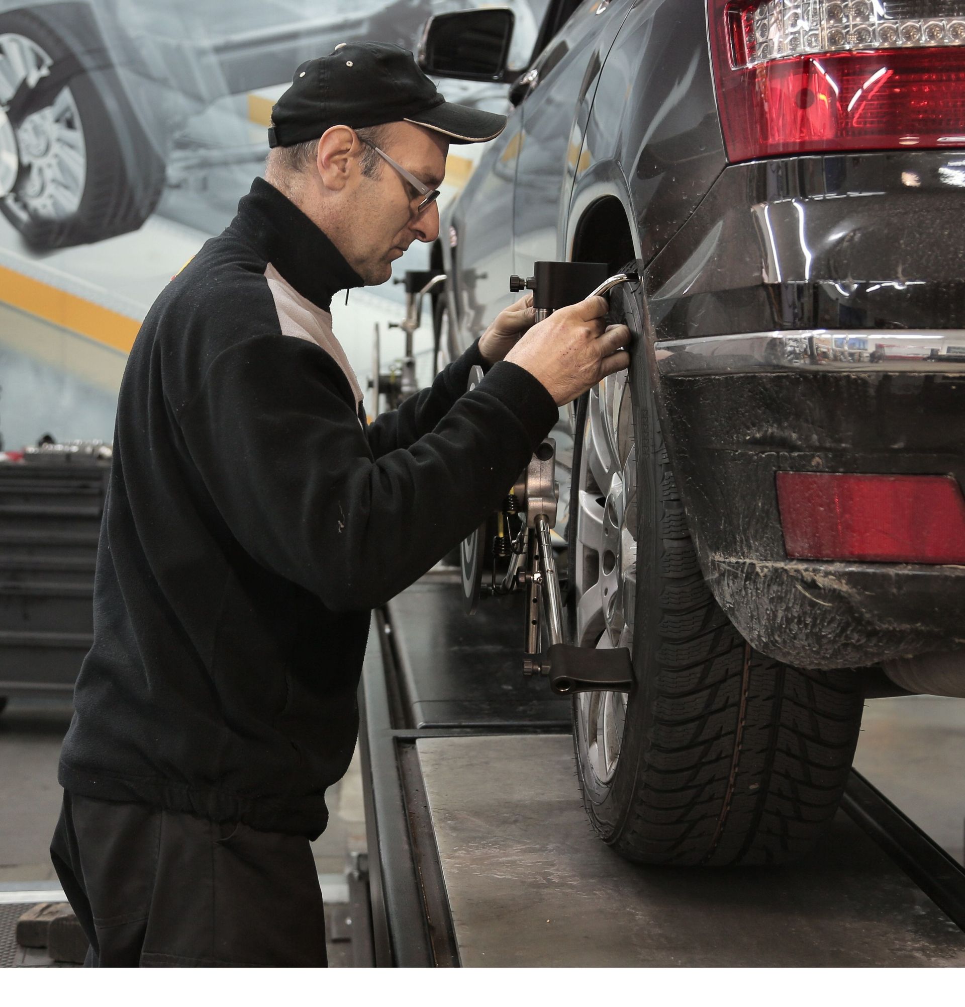 Mechanic inspecting a car’s rear wheel on an automotive lift in a repair shop