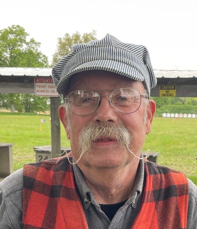 A man with a mustache wearing a hat and suspenders