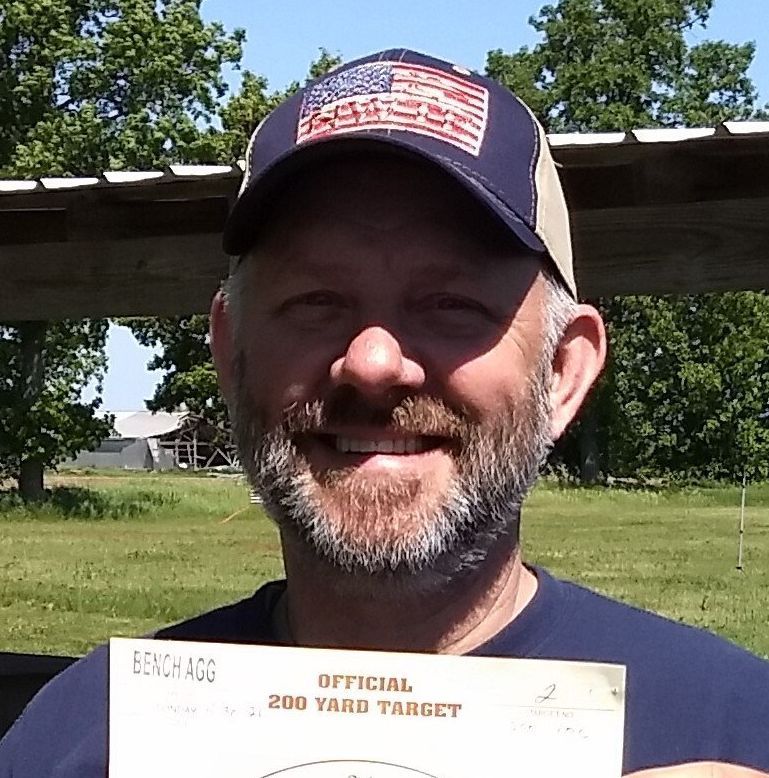 A man wearing an american flag hat is holding a 200 yard target