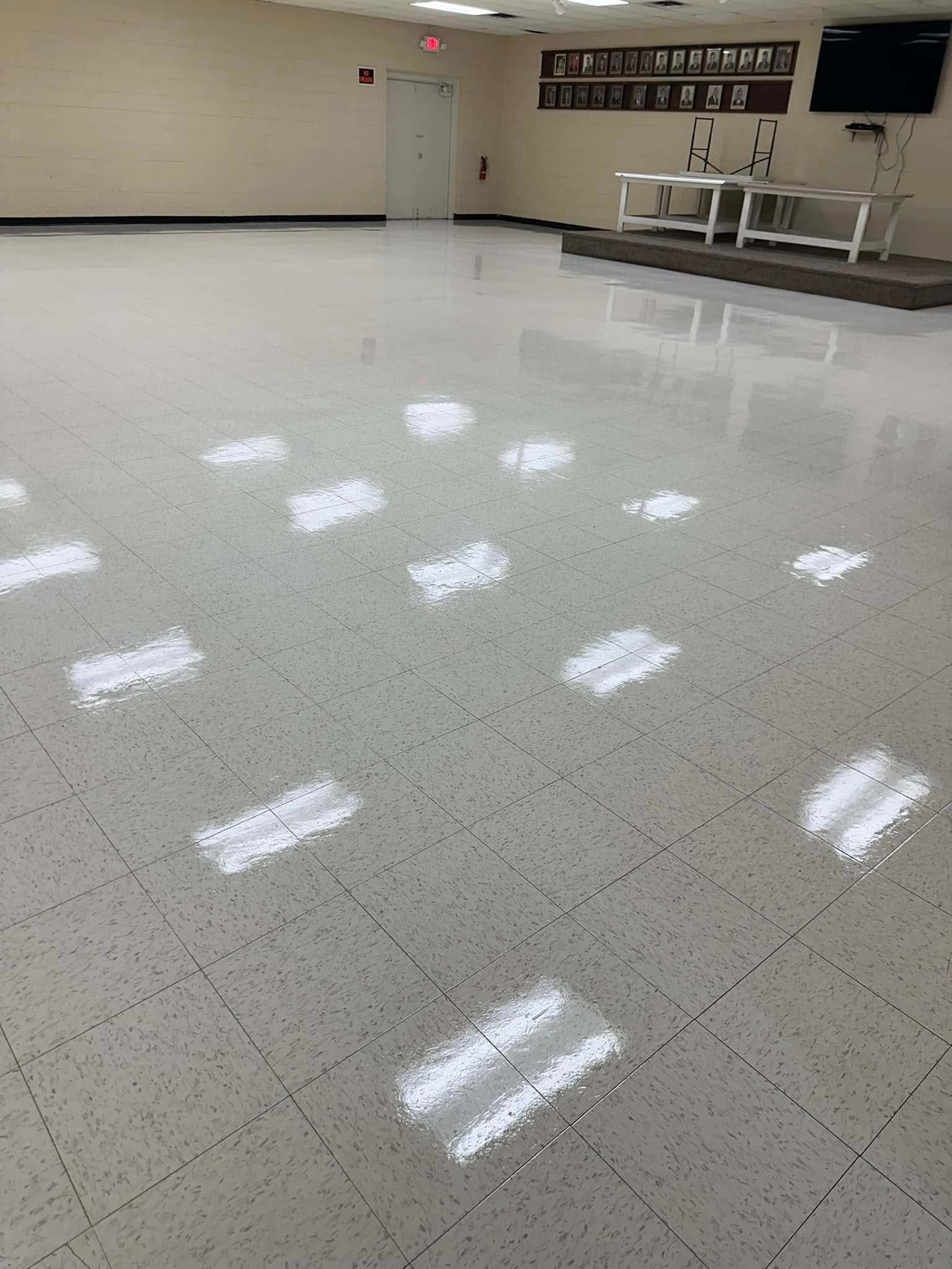 White tiled floor reflecting overhead lights in a large empty room.