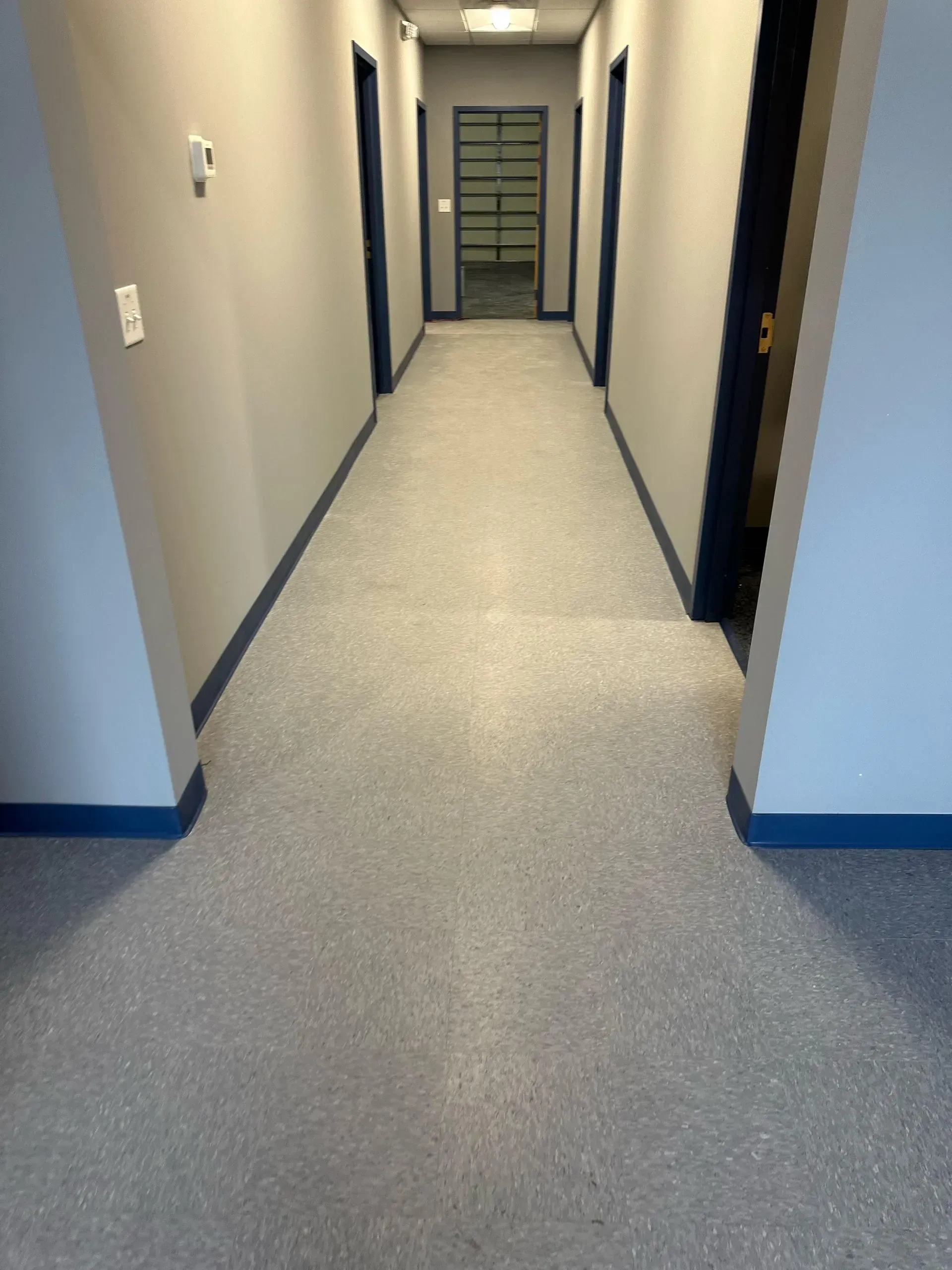A long hallway with a carpeted floor in a building.