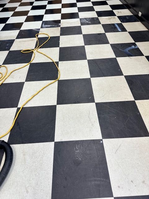 Black and white checkered floor with a yellow cord and vacuum hose.
