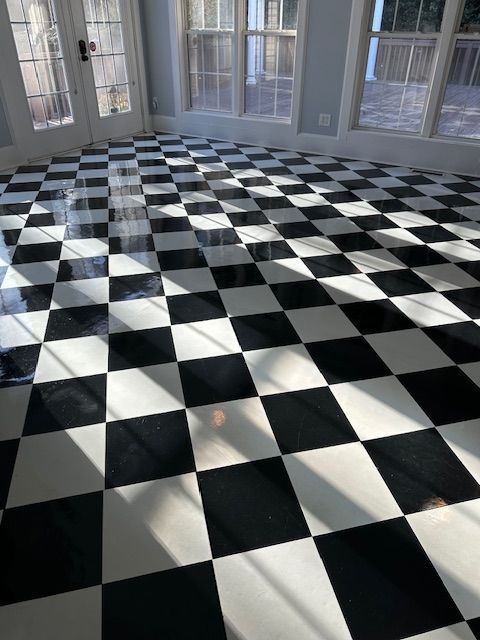 Black and white checkered tile floor in a sunlit room, with windows and a door visible.