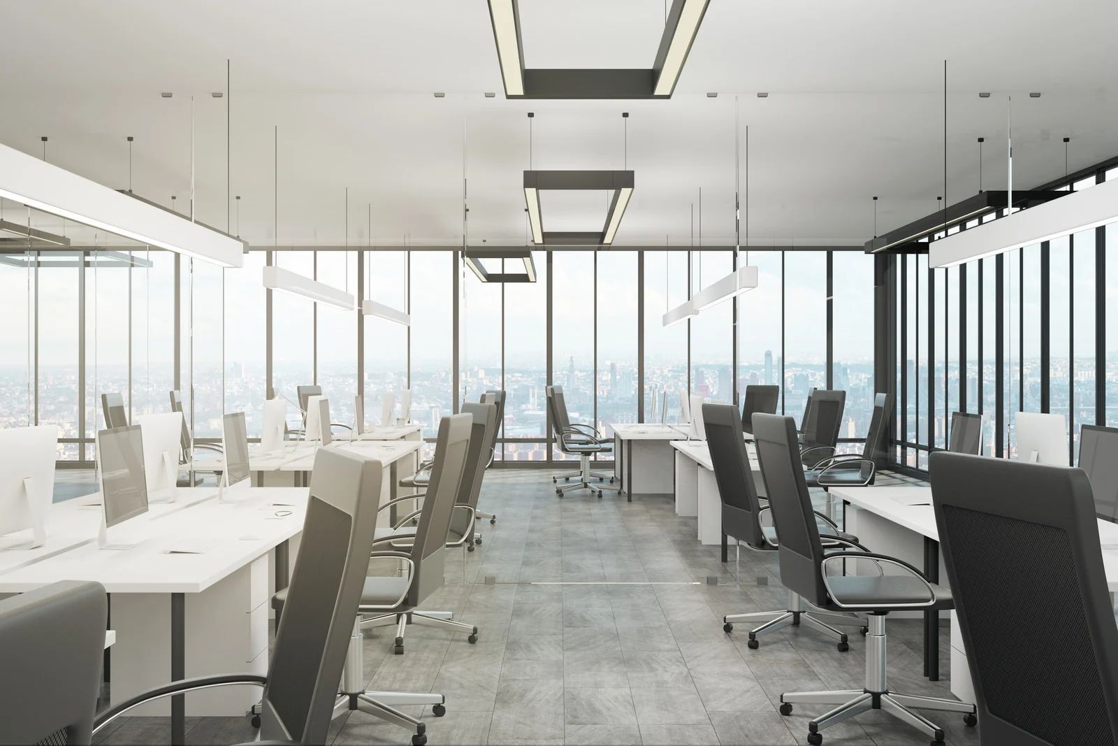 Modern office with rows of desks, chairs, and large windows overlooking a city skyline.