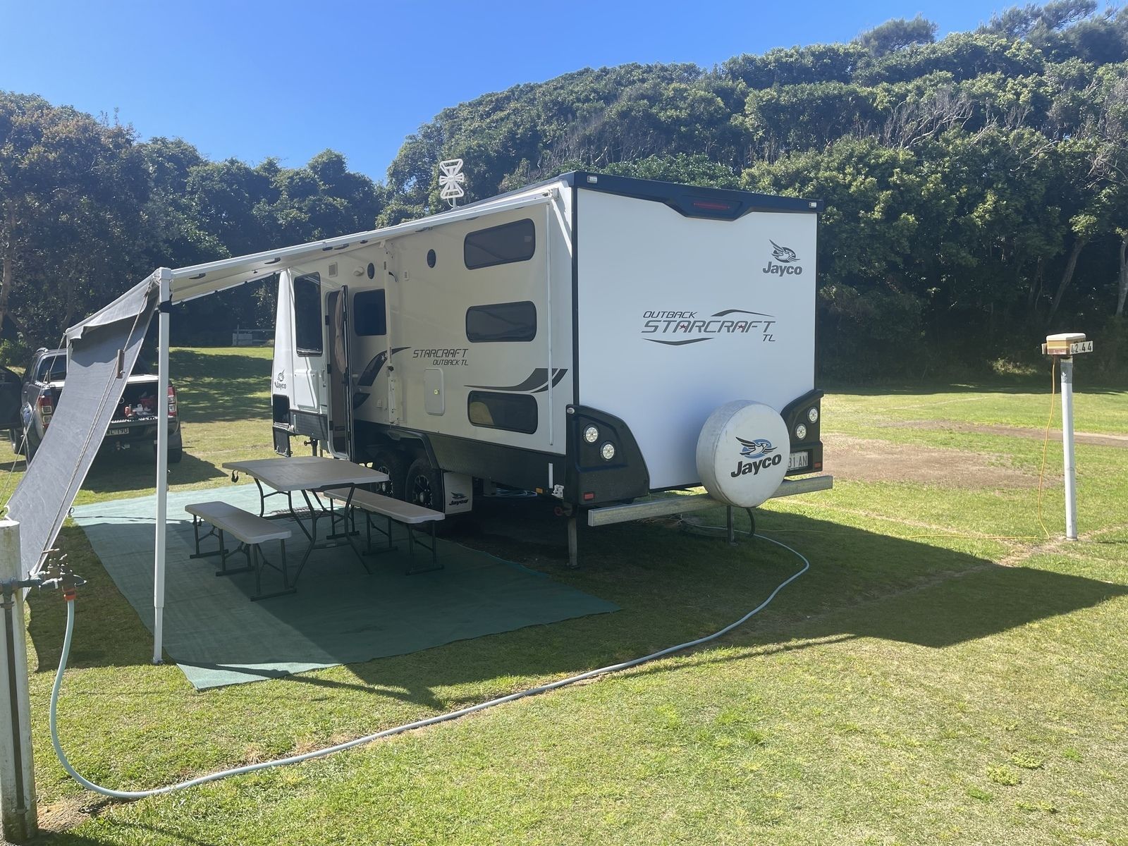 Family Fun Mnc Rv Is Parked In A Grassy Field With A Table And Chairs – Kempsey, NSW - Ezy Group Services