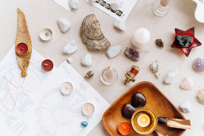 Assortiment de cristaux, de bougies et d'objets rituels sur une surface claire.
