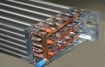 A close up of a metal coil with copper pipes on a table.