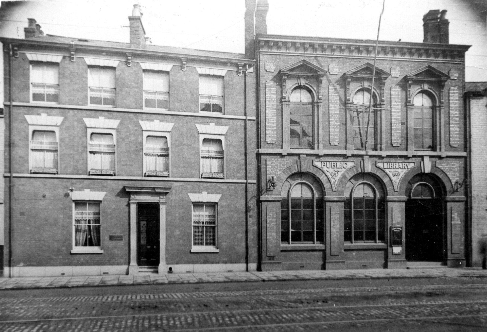 Buildings on a cobblestone street. Brick structures with various window designs and architectural details.
