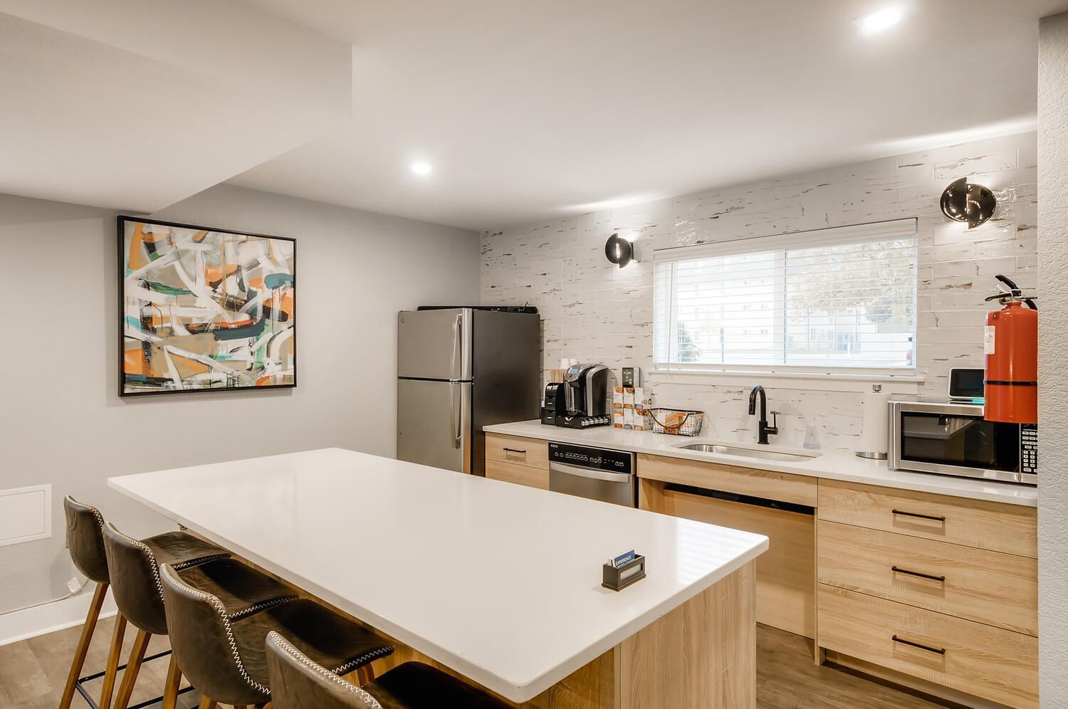 Open-concept kitchen in a modern apartment with a large island, white countertops, and stainless steel appliances.