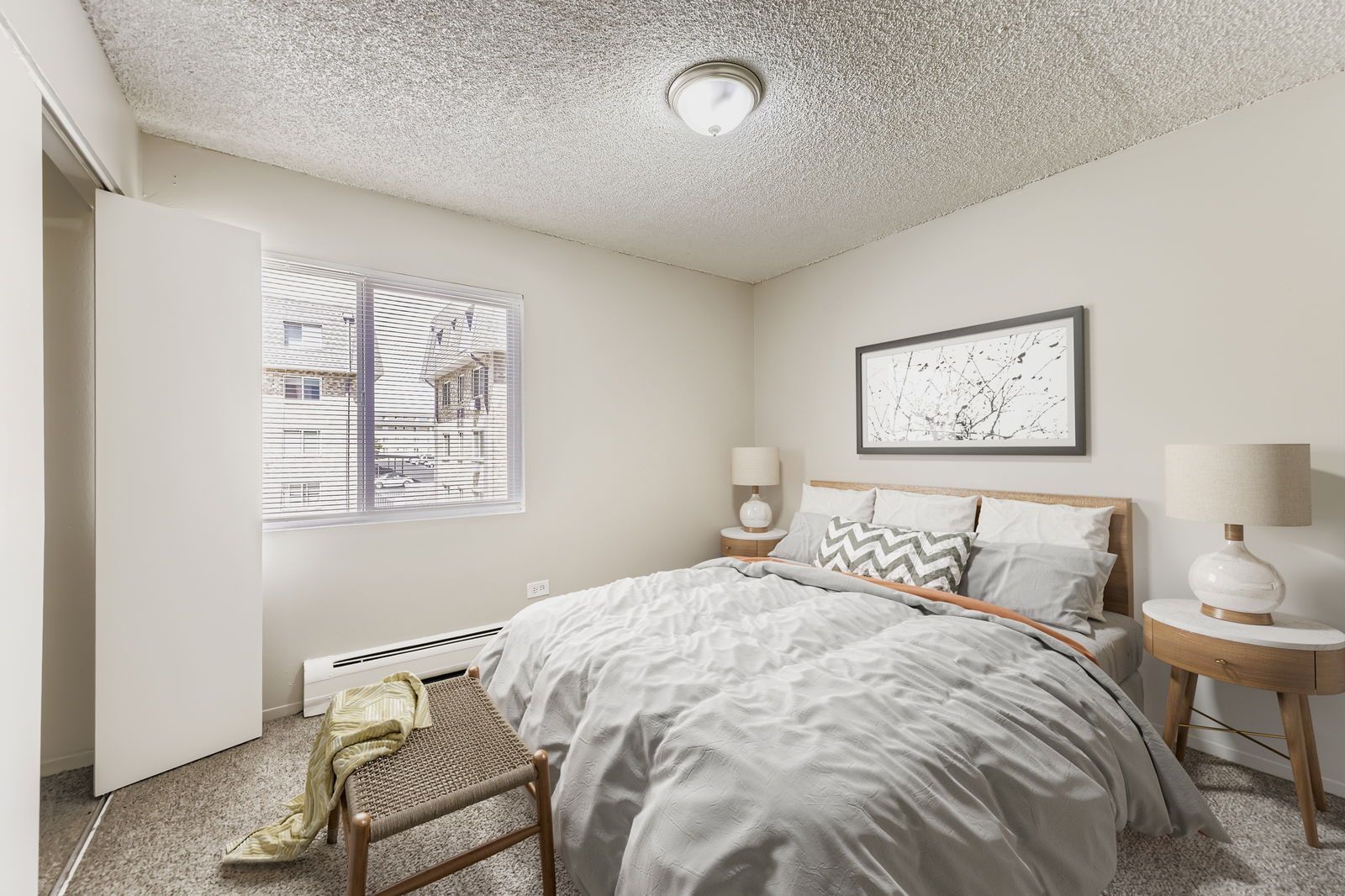 Bedroom with a bed, two nightstands, lamps, and a window with blinds.
