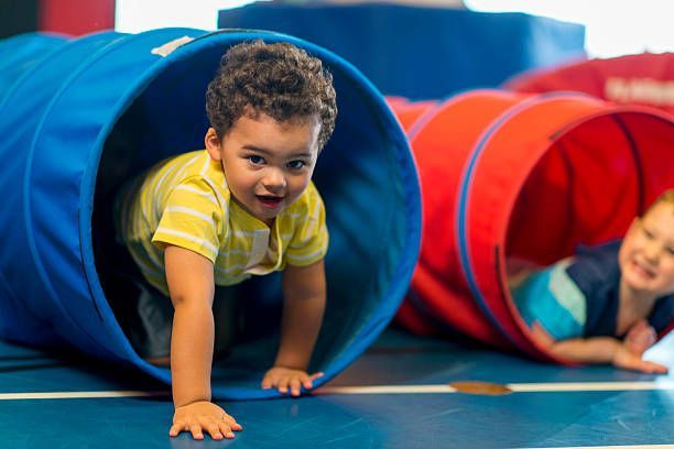 Two young boys are playing in a tunnel on the floor.