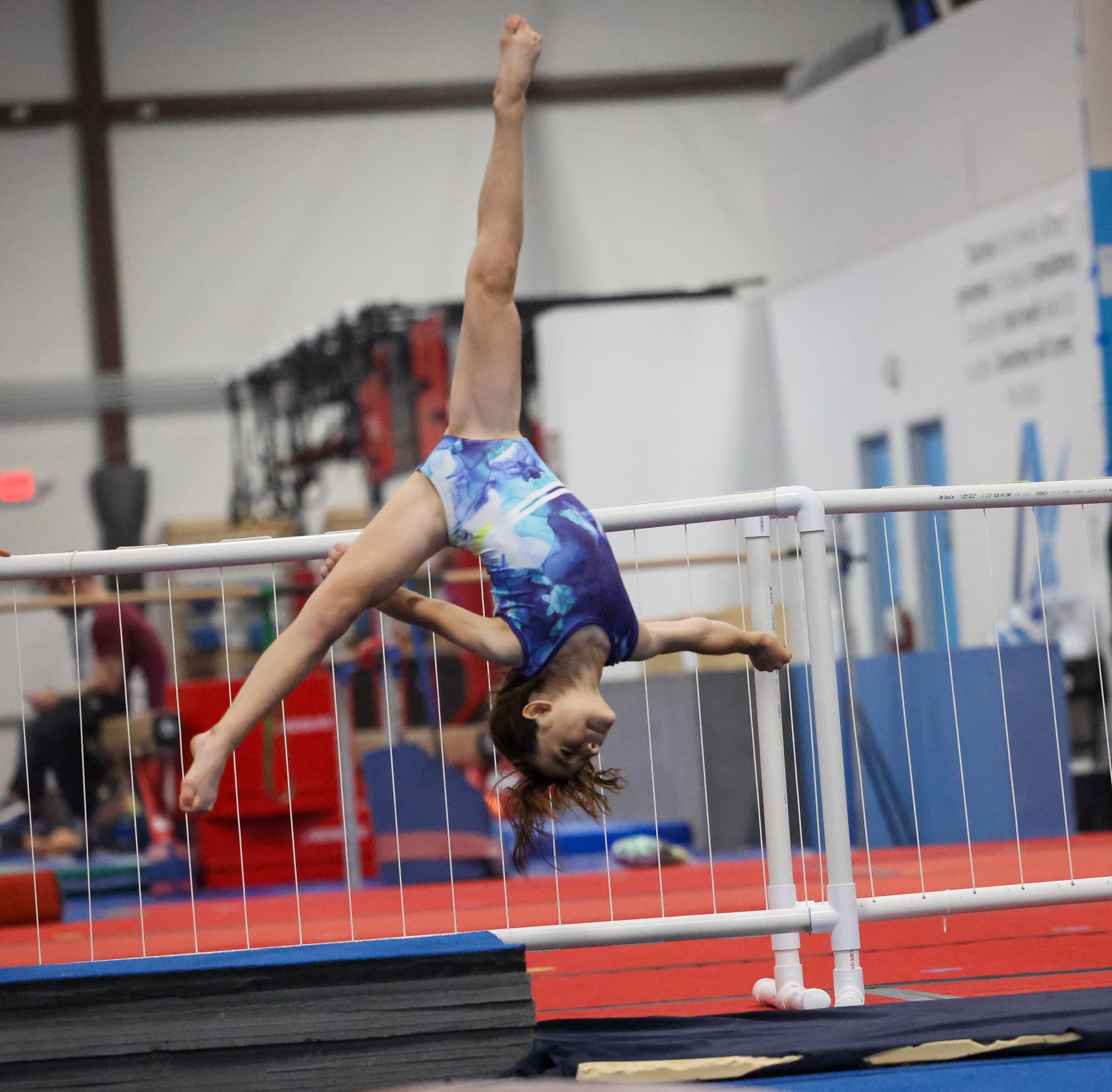 A young girl is doing a handstand on a balance beam