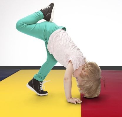 A little girl is doing a handstand on a colorful mat