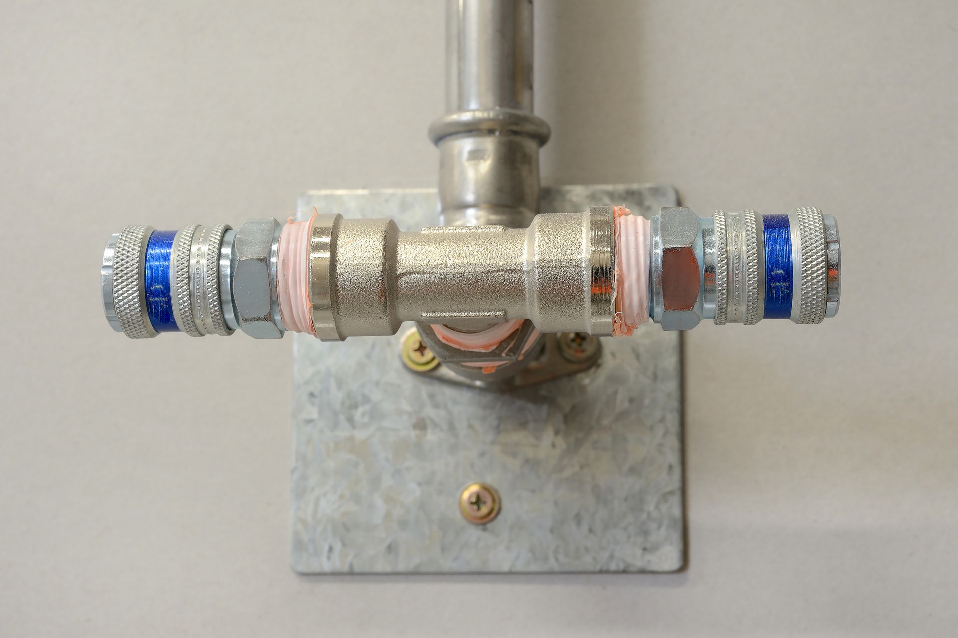 A technician in a blue uniform and cap inspects a water heater, holding a clipboard.