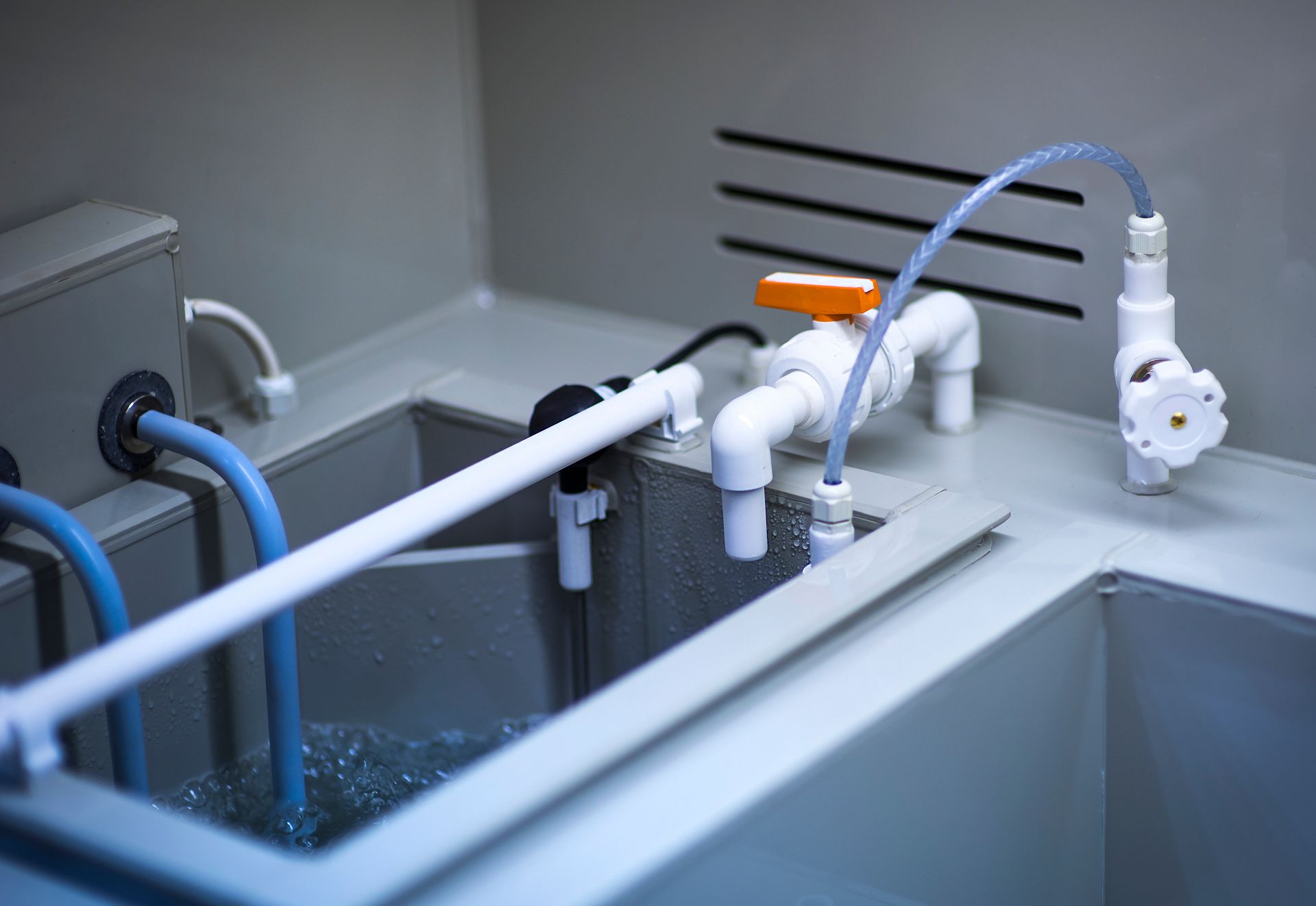 A sink with a lot of pipes coming out of it.