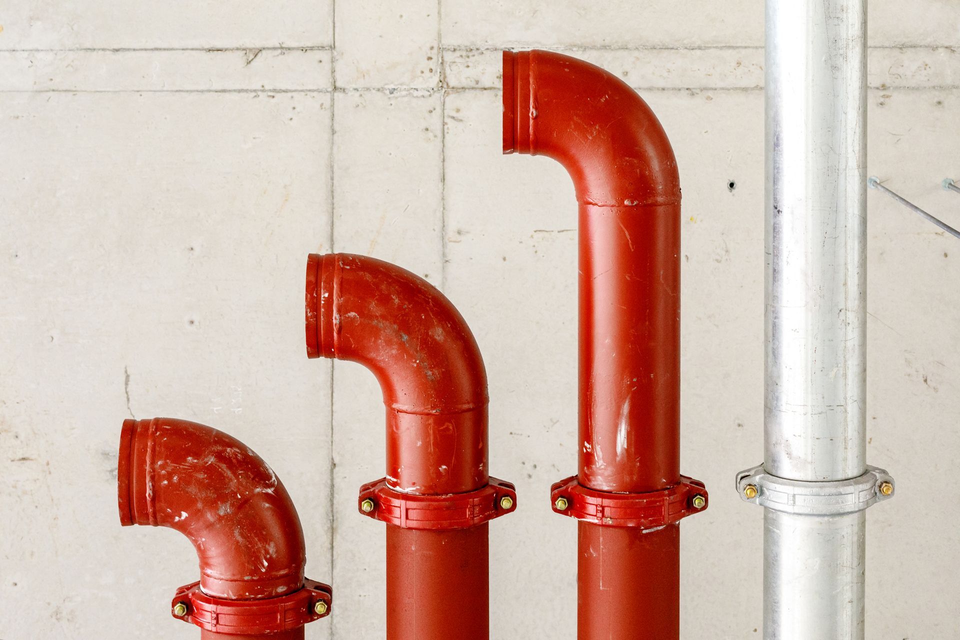 A man in a blue uniform checks a gauge on a system of insulated pipes in an industrial setting.
