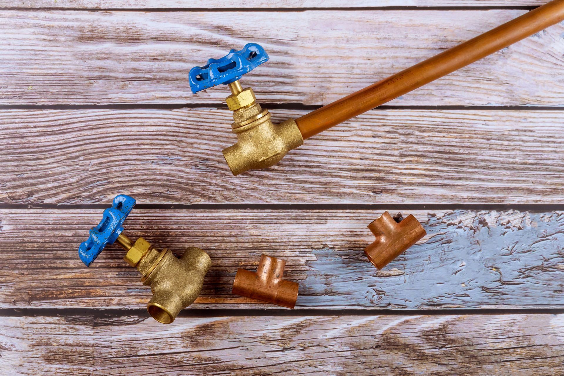 Woman in yellow gloves calls on phone while water leaks from under a bathroom sink. She has a worried expression, and a red bucket is in the corner.