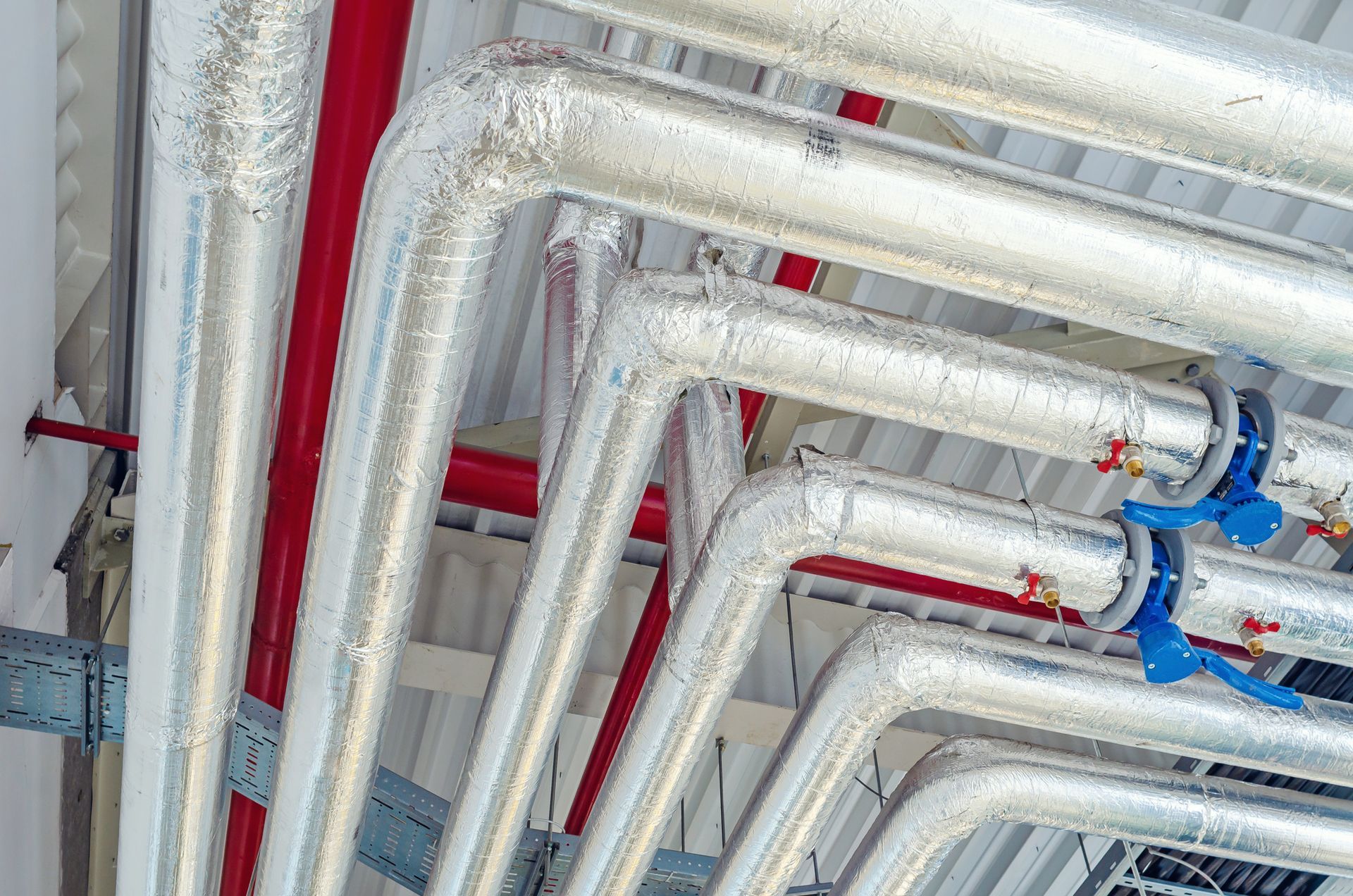 A plumber in blue overalls working on a heating system, with a toolbox nearby.