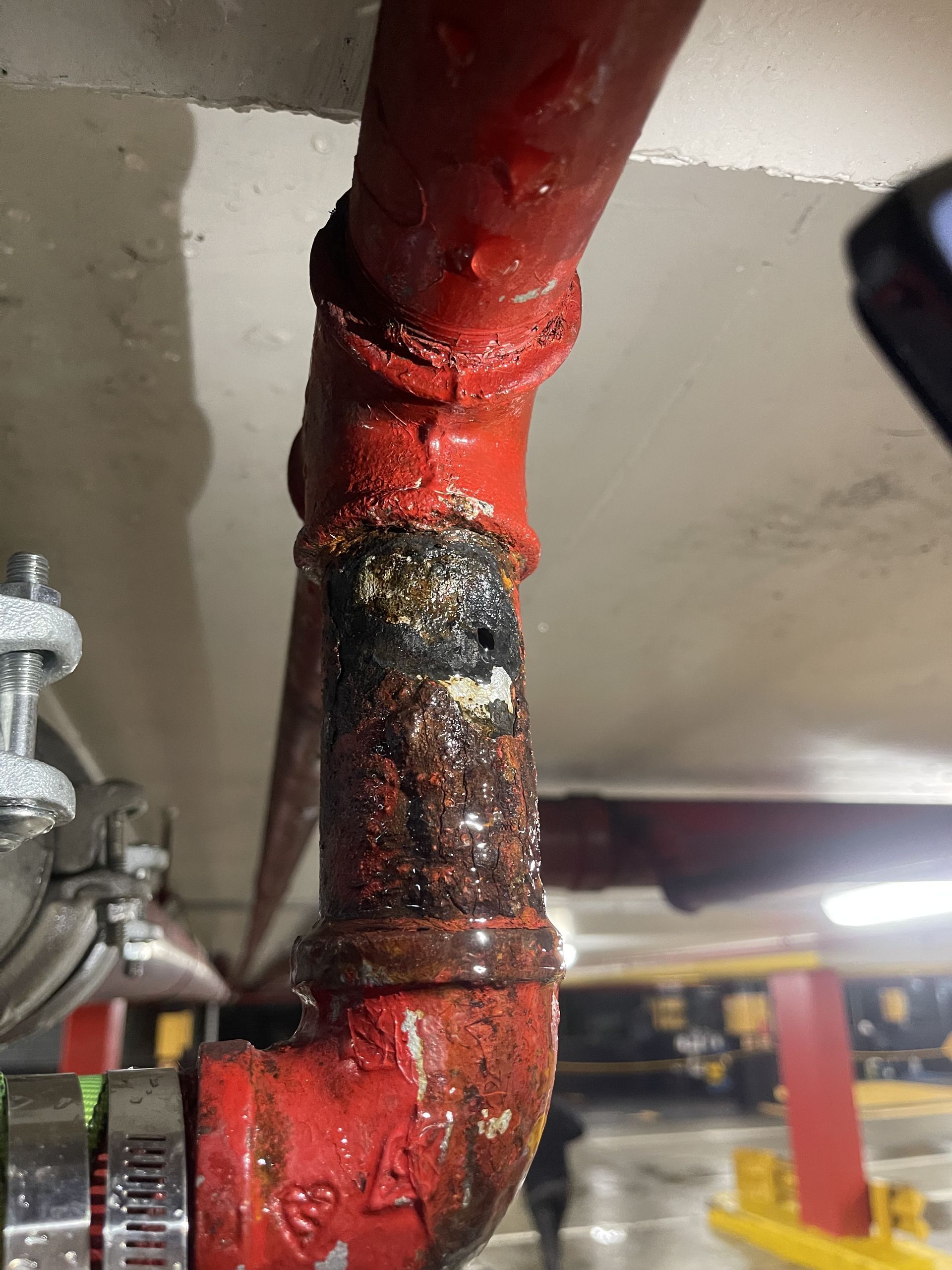 A person using two wrenches to work on plumbing under a sink.