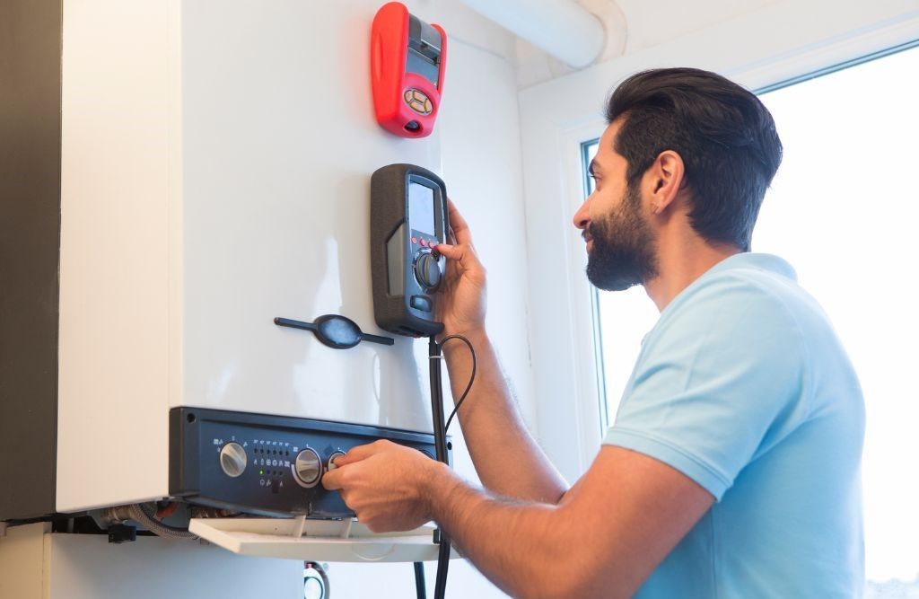 A man is working on a boiler in a kitchen.
