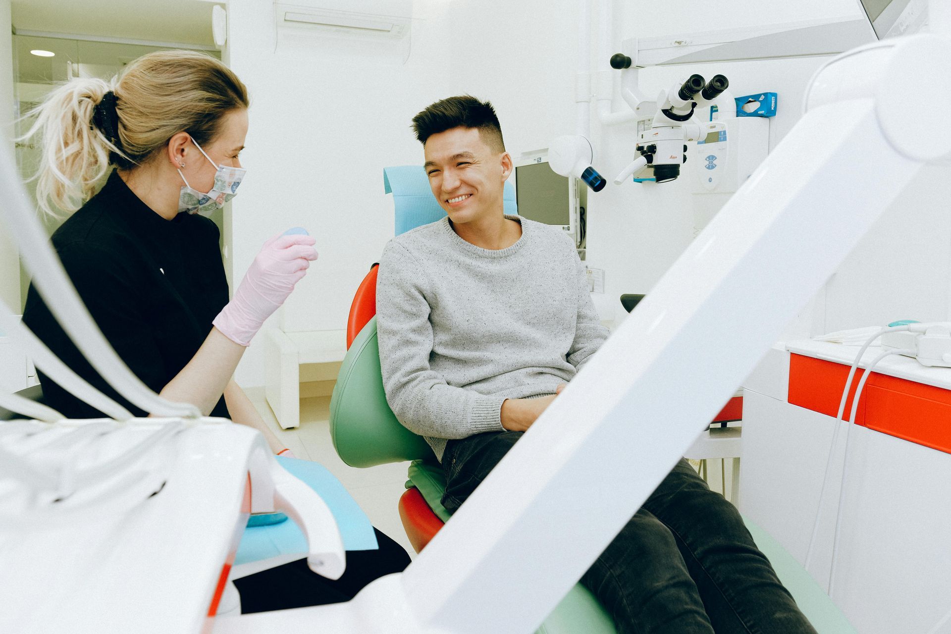 Man in dentist chair smiling at dentist wearing mask and gloves. Dental office setting.