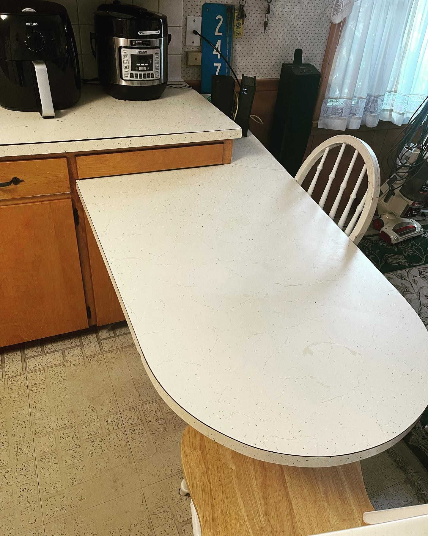 After is a spotless kitchen with a very shiny white table and a chair