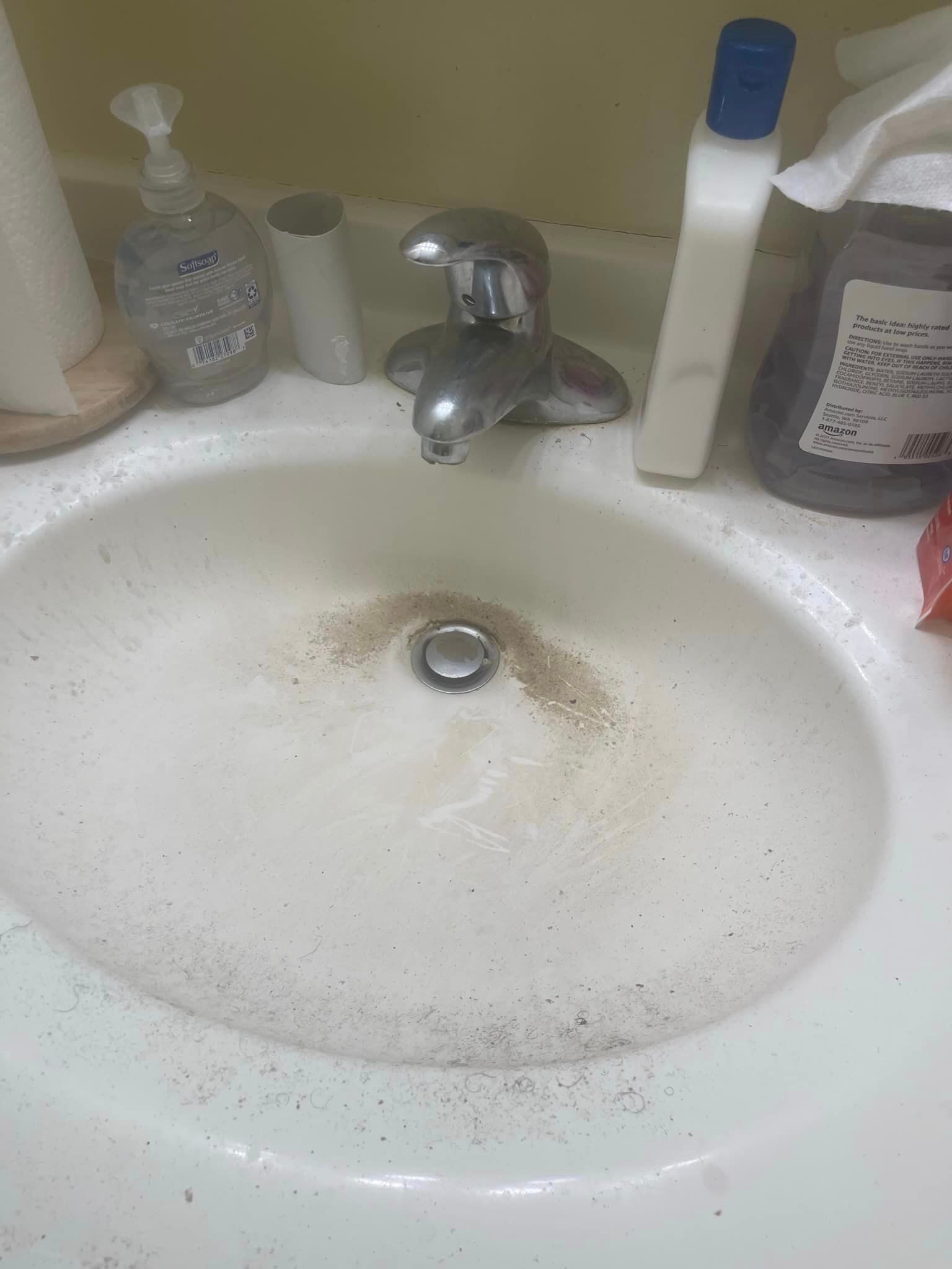 Before is a dirty bathroom sink with a faucet and soap bottles on the counter 