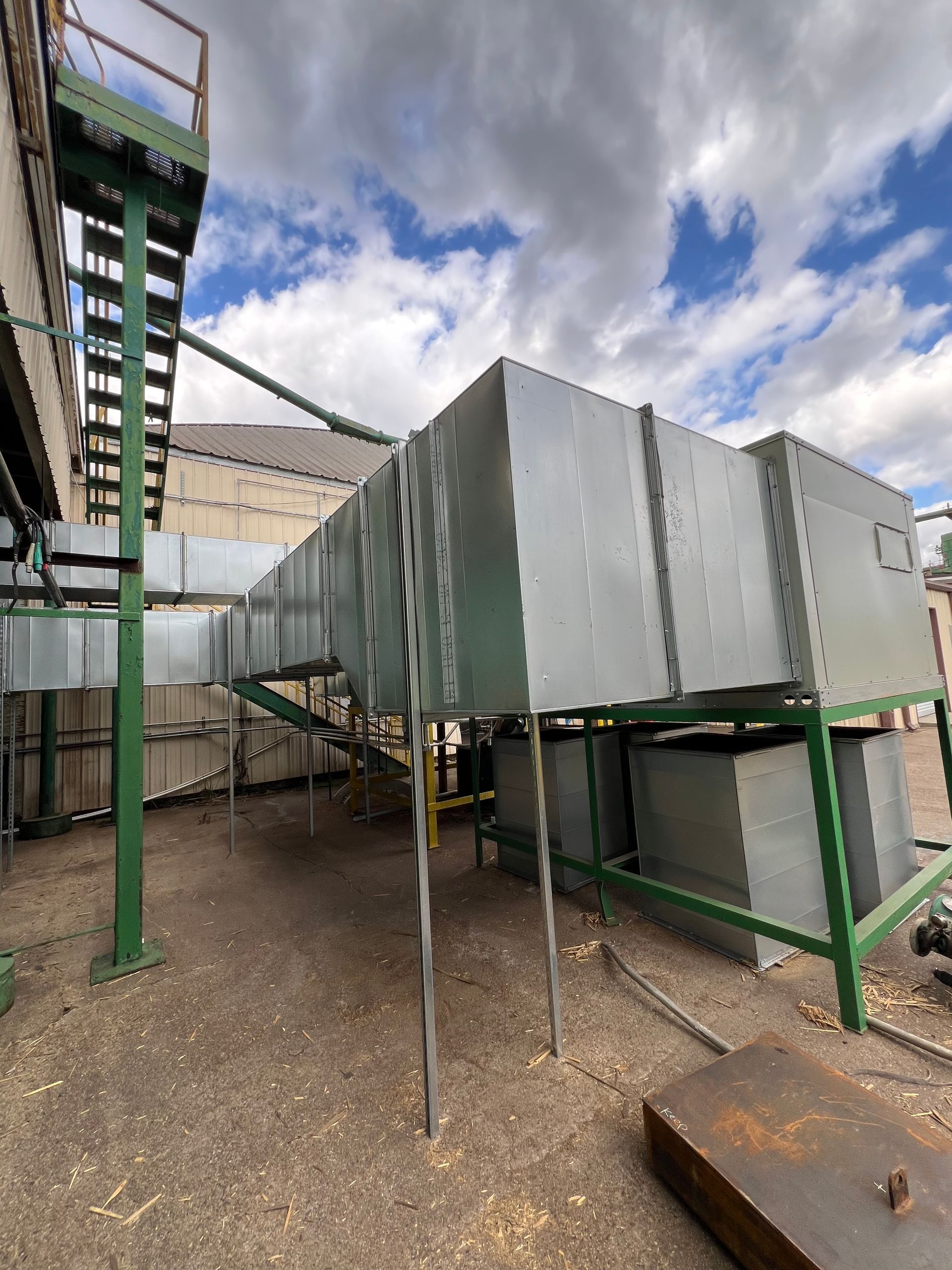 A large metal structure with stairs leading up to it is sitting on top of a dirt field.