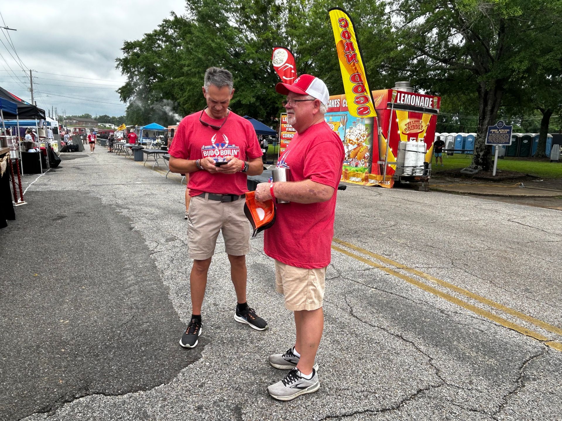 Two men are standing on the side of the road talking to each other.