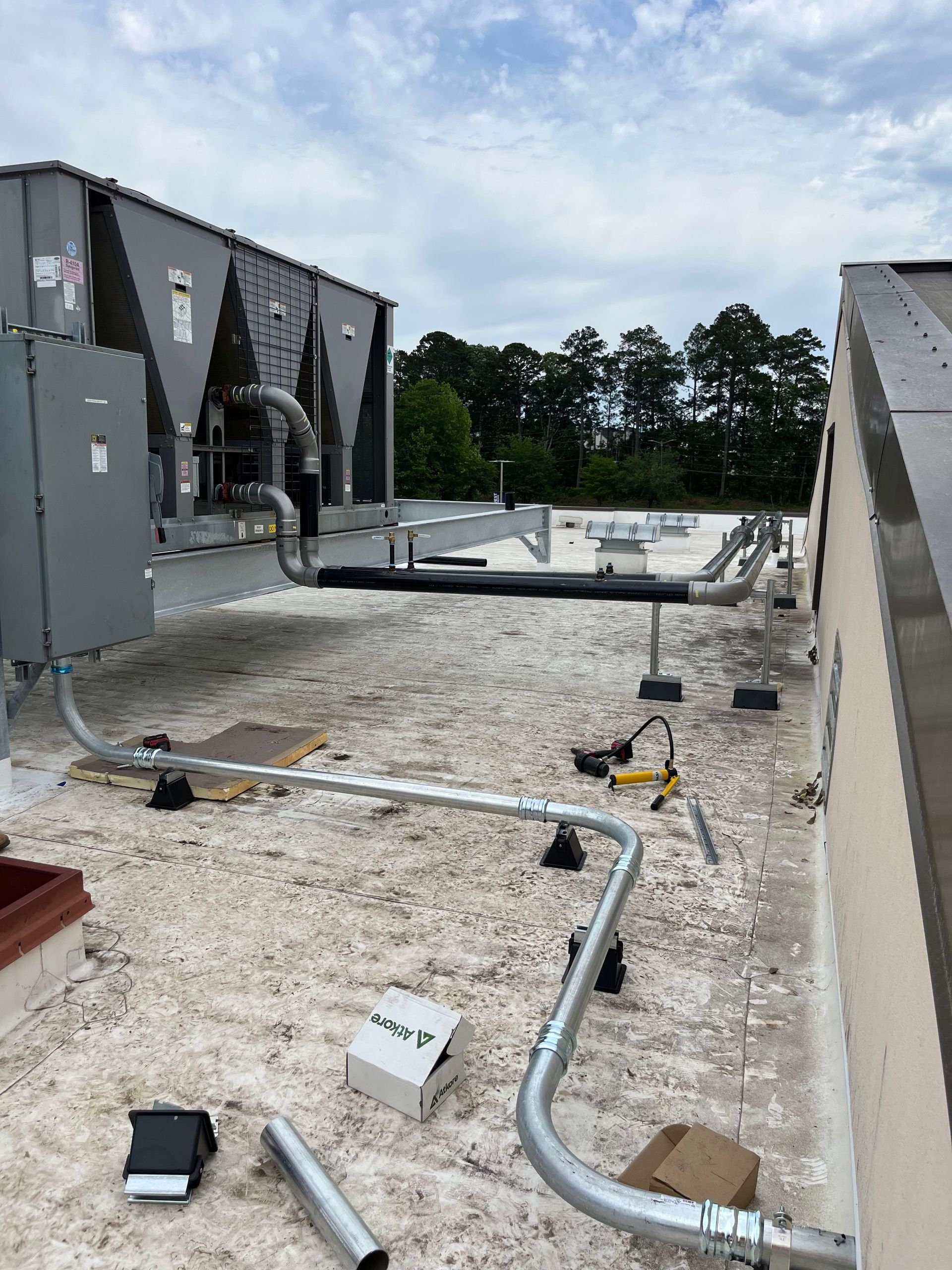 A roof with a lot of pipes on it and a building in the background.