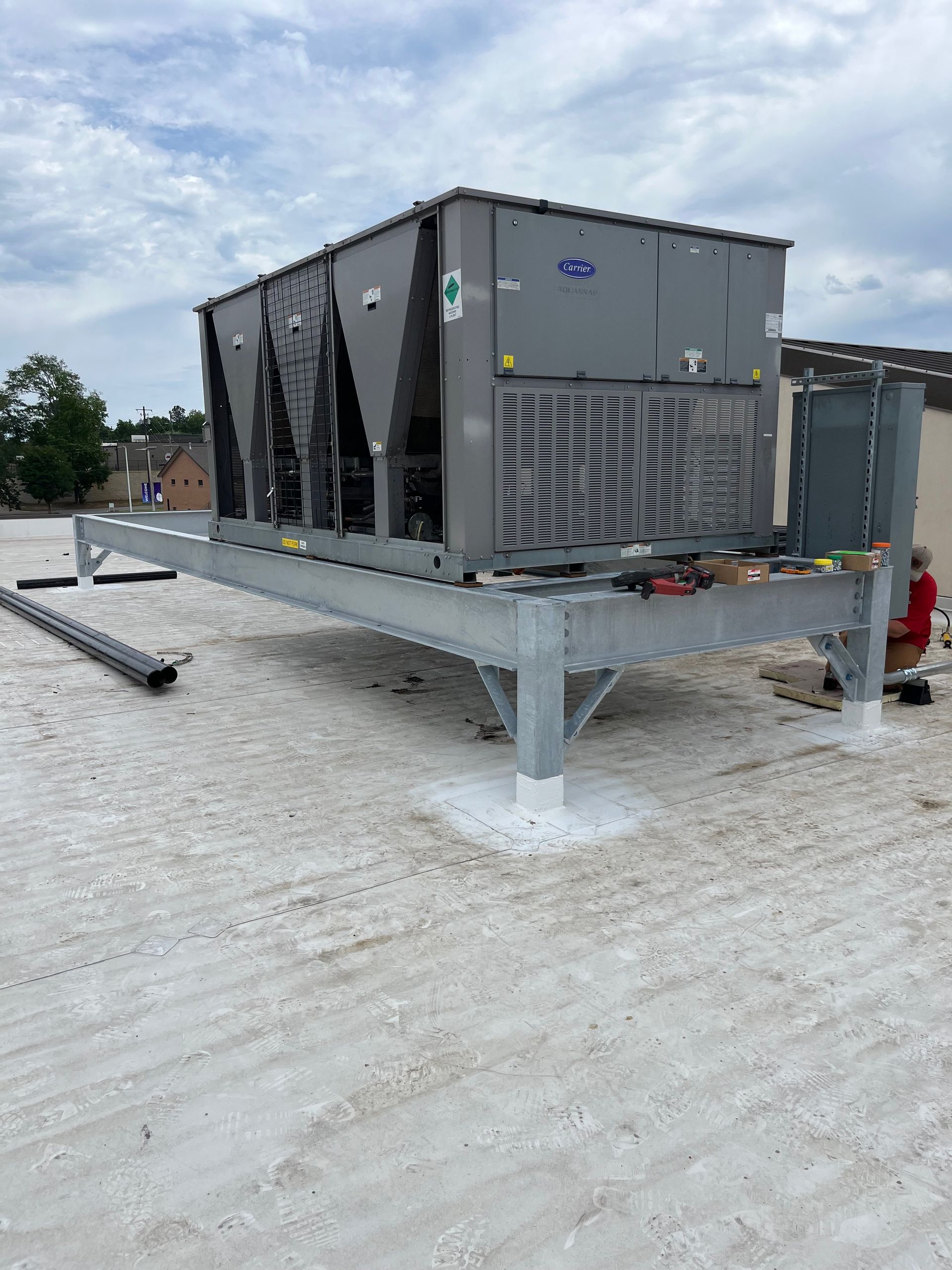 A large air conditioner is sitting on top of a white roof.