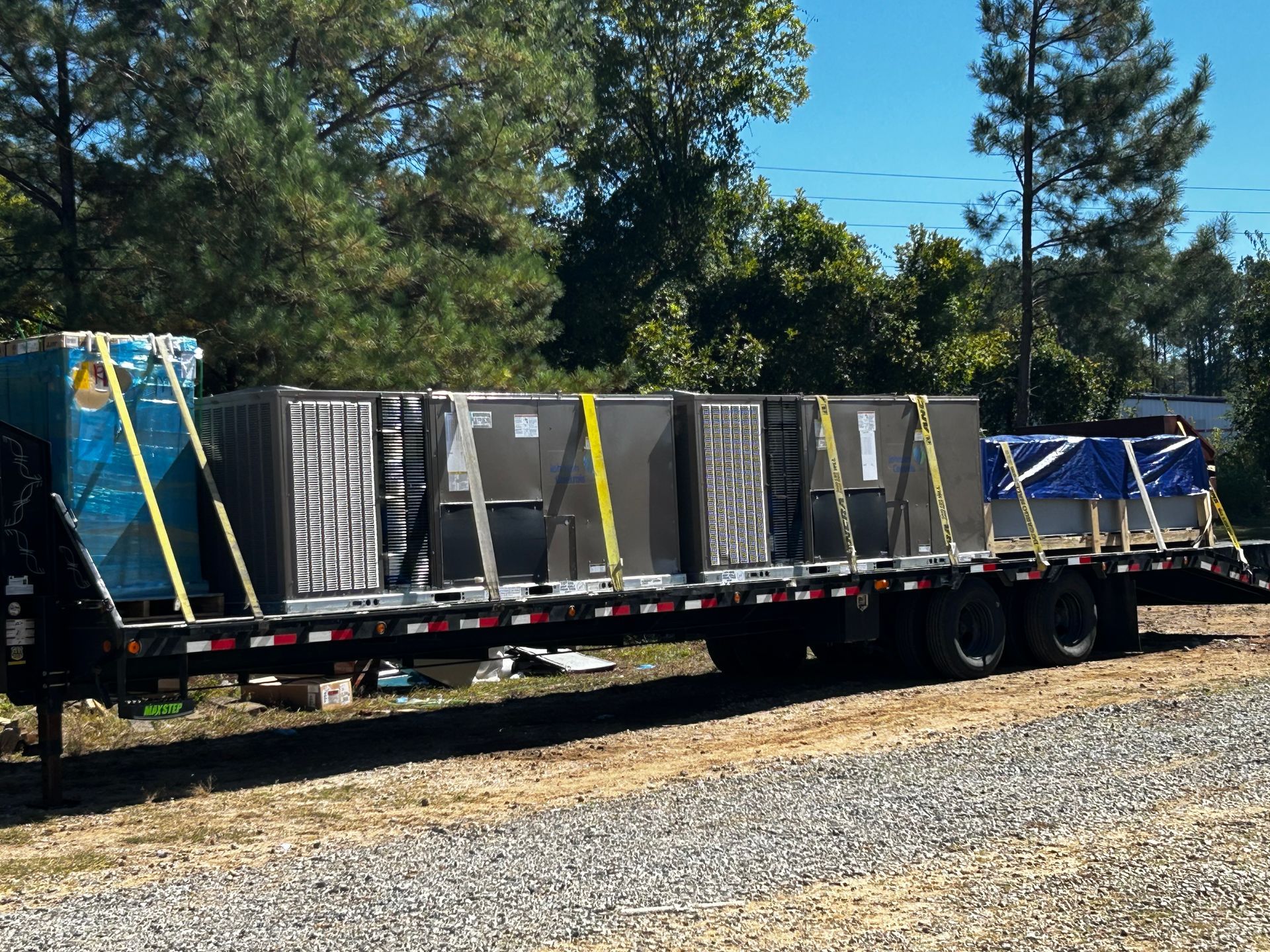 A trailer with a lot of boxes on it is parked in a gravel lot.