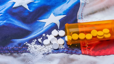 a box of pills is spilling out of a bottle on top of an american flag .