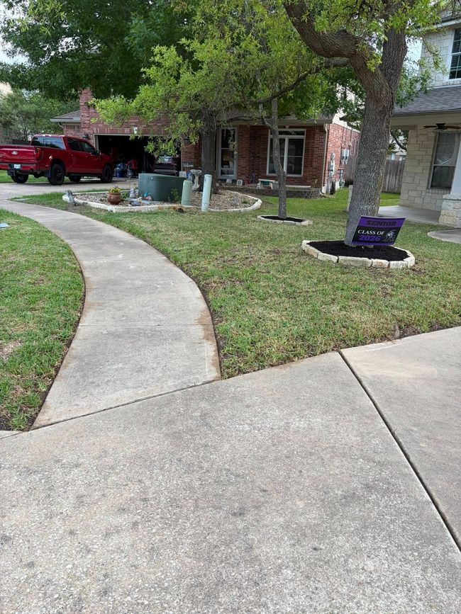 Curved sidewalk leading to a suburban house with a red truck, trees, and a purple mailbox