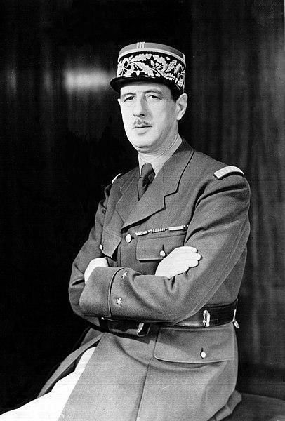 Le Général De Gaulle en uniforme militaire est assis, les bras croisés.
