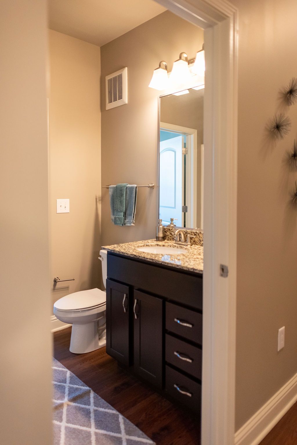 A bathroom with a toilet, sink, and mirror at 82 Flats.
