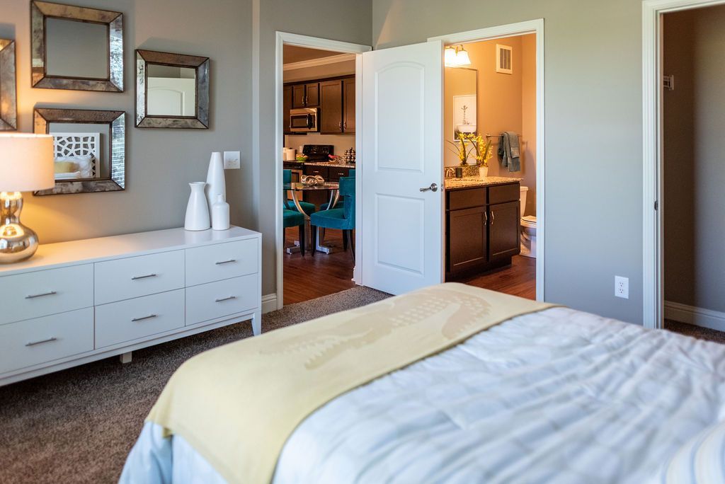 A bedroom with a bed, dresser, and mirrors at 82 Flats.