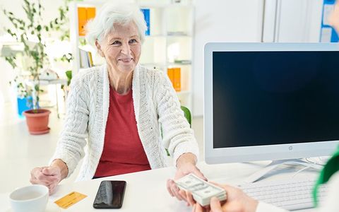 Senior lady storing money at bank - The Umbrella Insurance in Bowie, MD