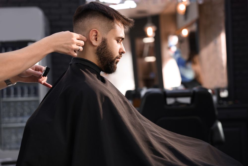 A man is getting his hair cut by a barber in a barber shop.