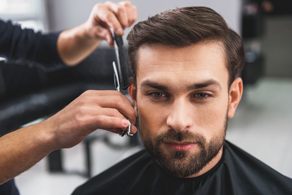 A man is getting his hair cut at a barber shop.