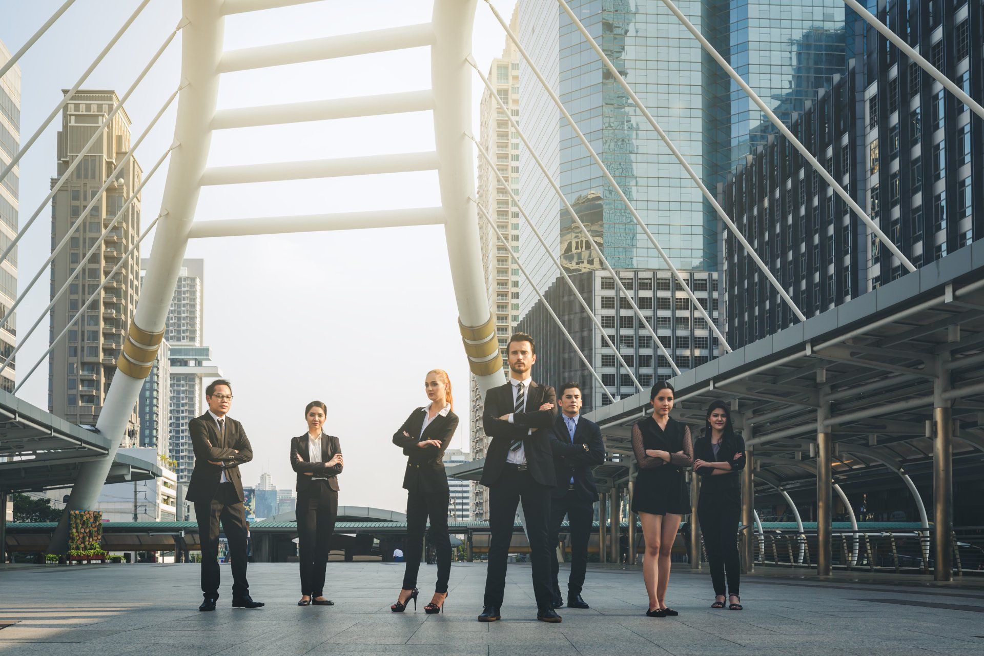 A group of business people standing next to each other in front of a bridge.