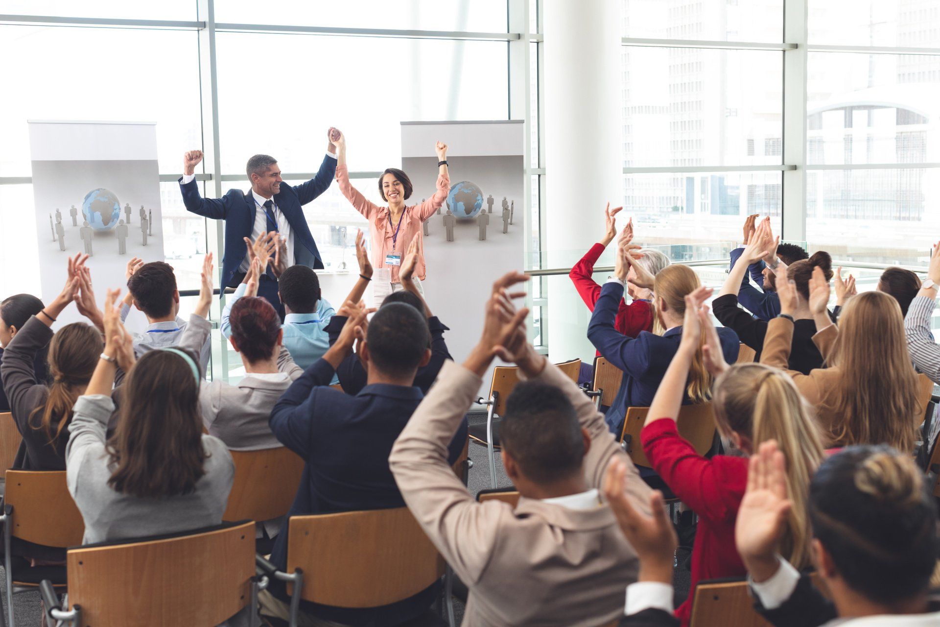 A group of people are sitting in a room with their hands in the air.